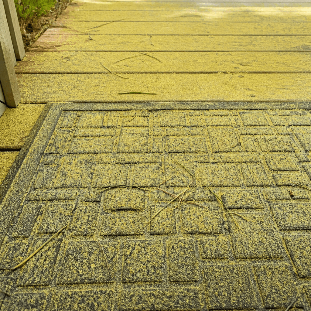 Yellow pine pollen coating a porch doormat and deck